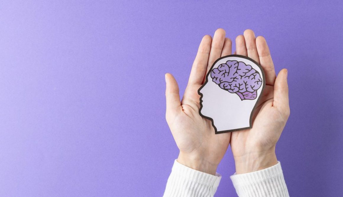 Hands holding image of paper head with brain