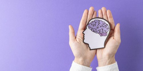 Hands holding image of paper head with brain