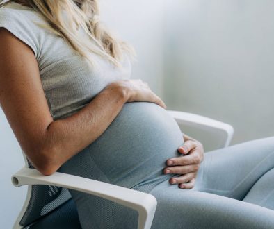 Woman holding her pregnant belly sitting in a chair