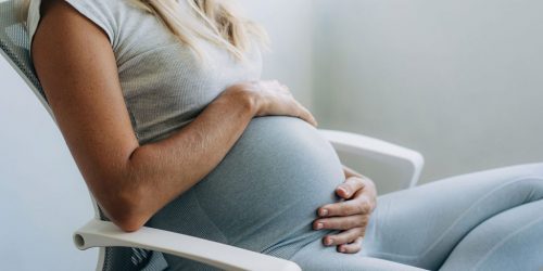 Woman holding her pregnant belly sitting in a chair